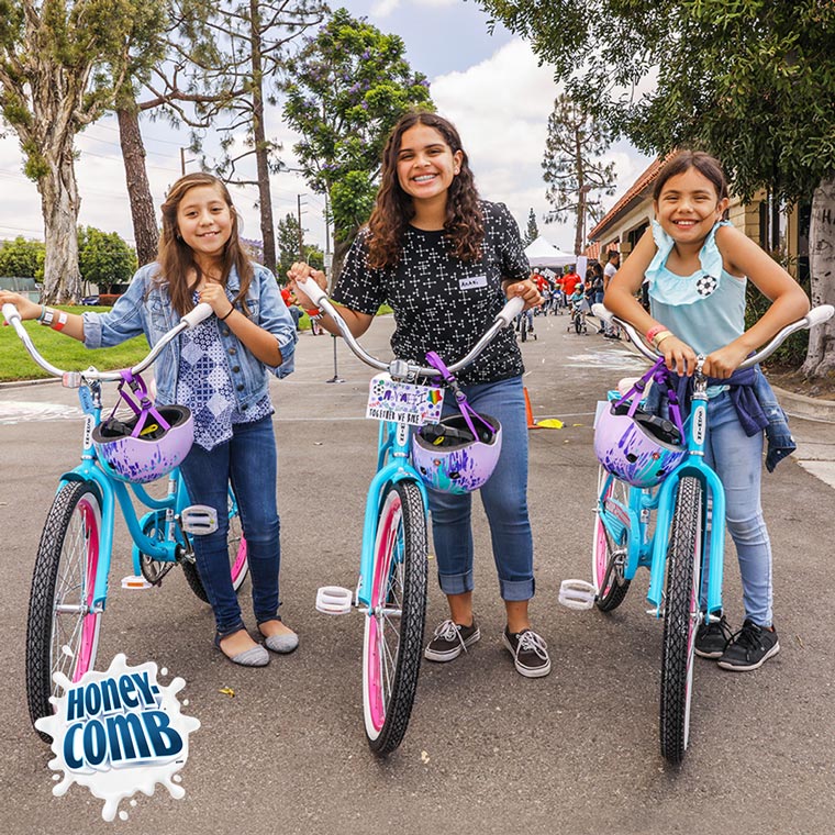 Image of kids sitting on bikes looking towards the camera smiling
